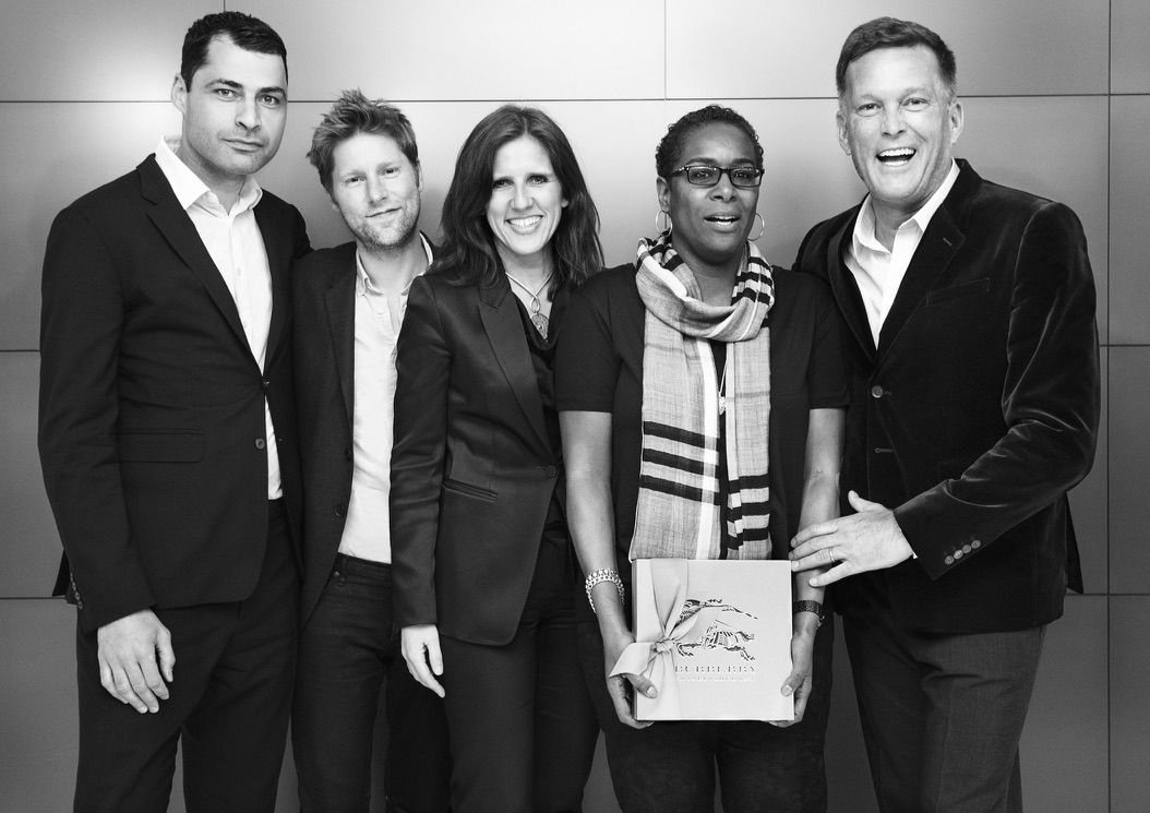 Black-and-white photo of Claudia with four others at Burberry, one of them holding a Burberry gift box