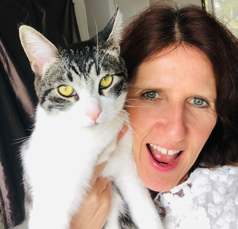 Claudia holding a grey and white tabby cat up to her cheek