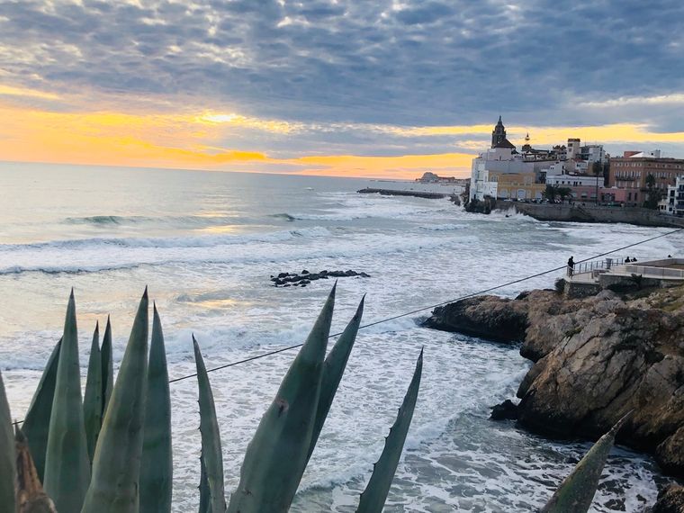 Waves breaking below a whitewashed church on the coast at Sitges, agave in the foreground